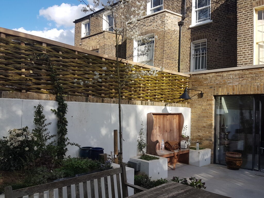 framed willow hurdle on a wall in a contemporary urban garden in London