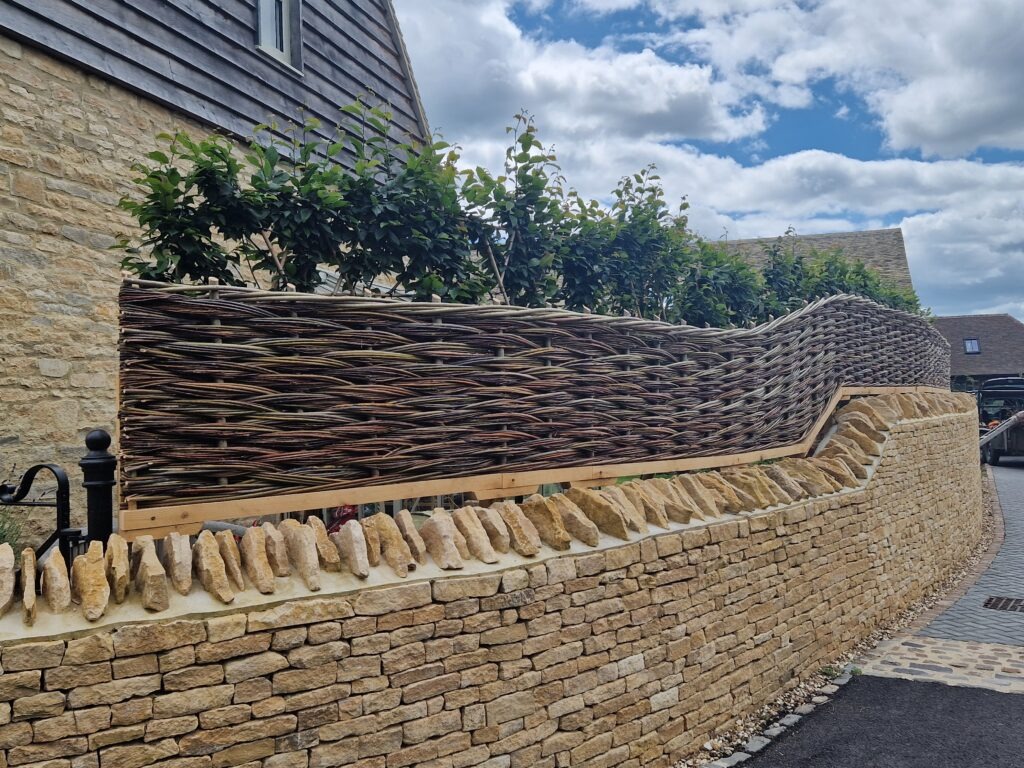 willow hurdle atop a dry stone wall for privacy in an urban garden